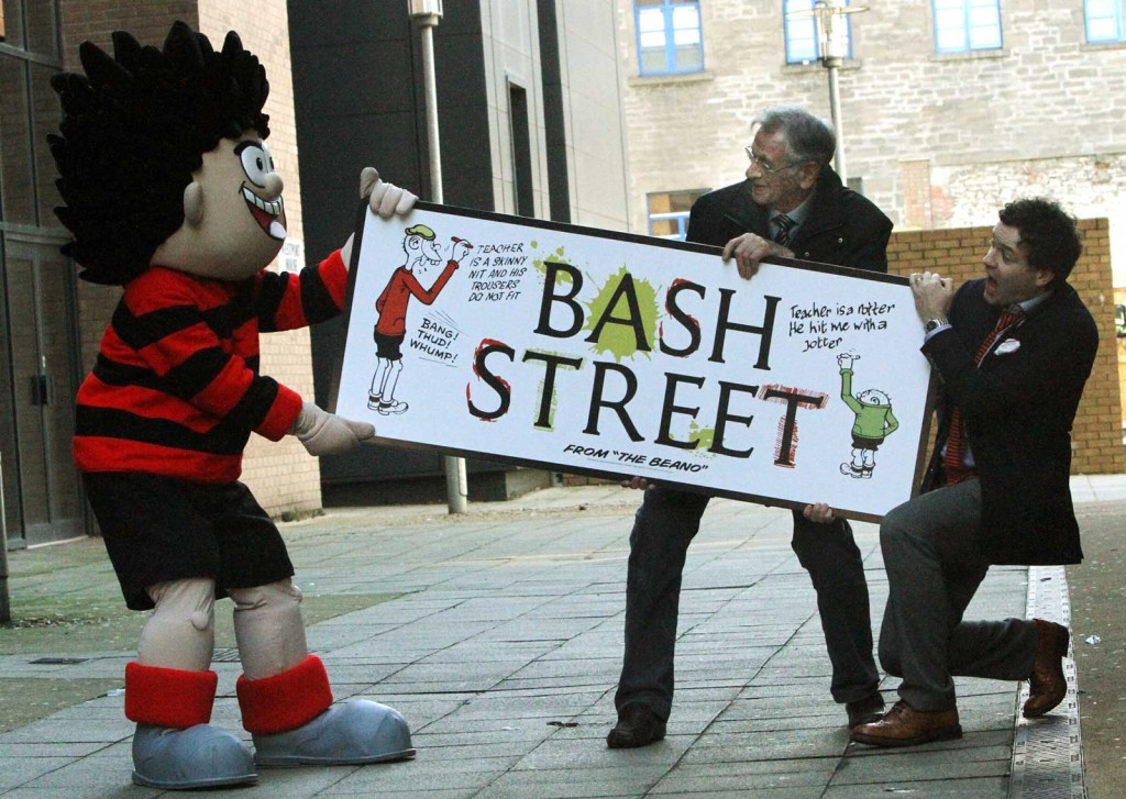 Pictured in the newly named 'Bash Street' in Dundee on Wednesday 26th February 2014, is Dennis The Menace trying to steal a copy of the sign, with Beano Editor Mike Stirling, right, and Dave Sutherland, who draws Dennis. Photo: The Courier. Reproduced with permission