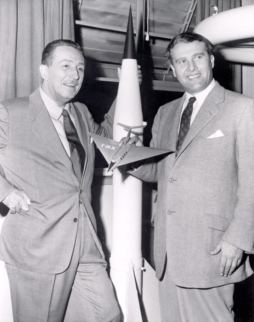 Walt Disney, left, and Wernher von Braun, right. Dr. Werhner von Braun, then Chief, Guided Missile Development Operation Division at Army Ballistic Missile Agency (ABMA) in Redstone Arsenal, Alabama, was visited by Walt Disney in 1954. In the 1950's, von Braun worked with Disney Studio as a technical director, making three films about space exploration for television. A model of the V-2 rocket is in background.