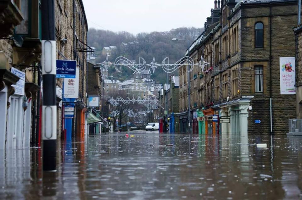 2 Tone Comics in Hebden Bridge (the orange-coloured shop on the right hand side of this photograph) was one of many businesses devastated by recent floods, along with thousands of home owners across the North of England and Scotland. Photo: 2 Tone Comics