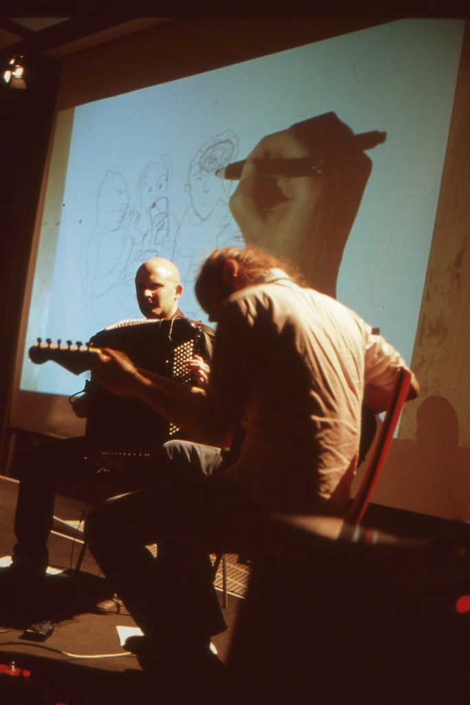 On stage: Ville Ranta, illustration; Aleksi Ranta, guitar; Niko Kumpuvaara, accordion.