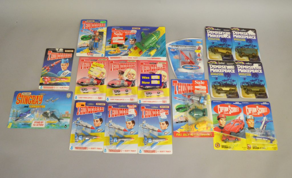 18 carded diecast TV related models including thirteen Matchbox Gerry Anderson related items - 10 x Matchbox Thunderbirds and 1 x Matchbox Stingray together with two Vivid Imaginations 'Captain Scarlet' models, additionally there are four from the Rainbow Toys 'Dempsey and Makepeace' range and an FEVA Thunderbird 3 carded model.
