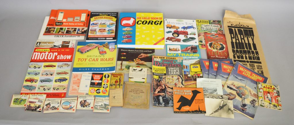 A small quantity of toy related books including 'The Great Book of Corgi' and 'Ramsay's Diecast Catalogue 14th Edition' together with a varied selection of books, publications and other paper ephemera including a vintage Chipperfield's Circus Programme, a Will's Cigarette Card Album containing a quantity of 'Household Hints' cards, humorous 'Hallmark' posters, 1974 Ercol Furniture Catalogue, two Aircraft Postcards etc.