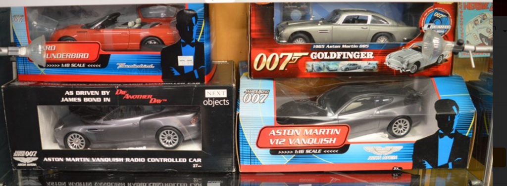 Four James Bond diecast model cars including an Aston Martin V12 Vanquish 1:16 scale