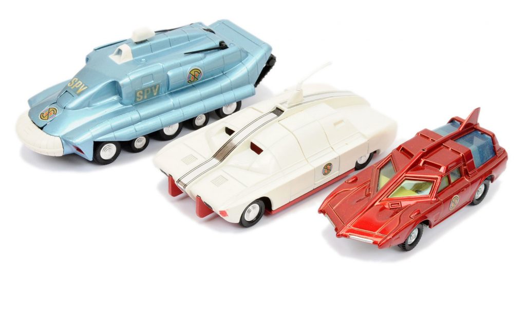 Dinky "Captain Scarlet", a group that includes a Spectrum Pursuit Vehicle - blue, white bumper, black rubber tracks, cast hubs, with missile; Maximum Security Vehicle (1st issue) - white, red base and interior, plastic aerial, cast spun hubs, with radiation box (missing side stripes); Spectrum Patrol Car - metallic red, blue tinted windows, white base, cast hubs (missing aerial)