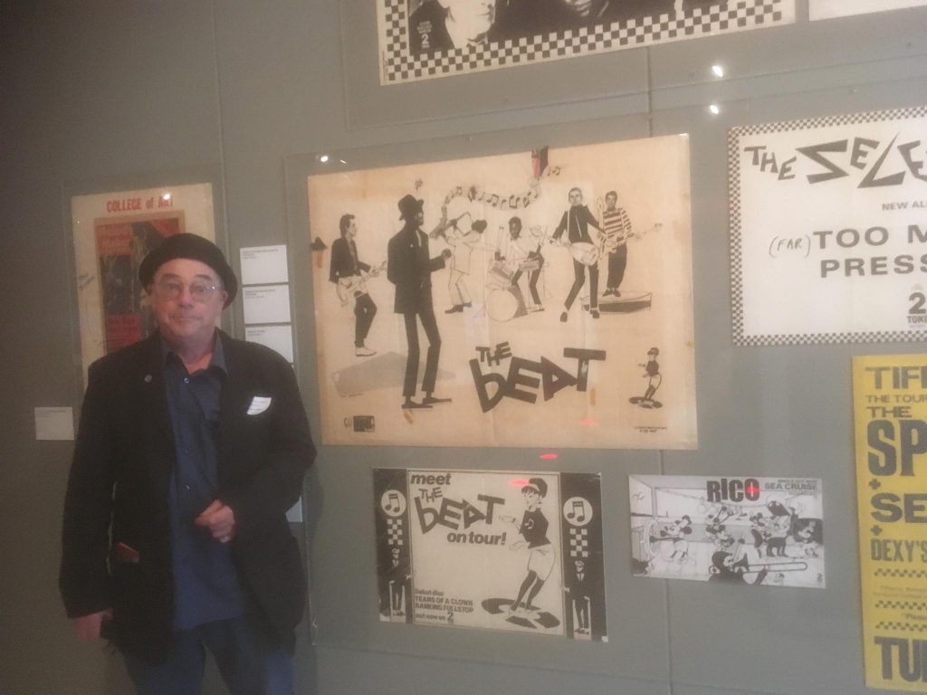 Hunt Emerson at the 2 Tone exhibition at the Herbert Art Gallery & Museum, in front of posters he created 40 years ago. Photo via Hunt Emerson