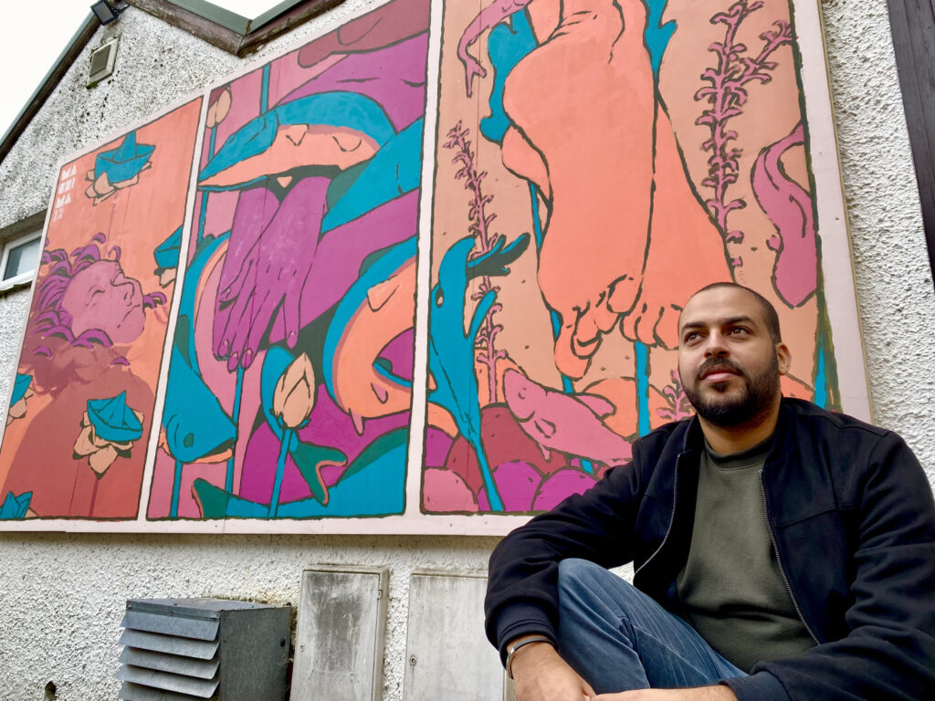 Mehdi Annassi alongside his Windermere Arctic Charr mural at the Lake District Boat Club for LICAF 2022