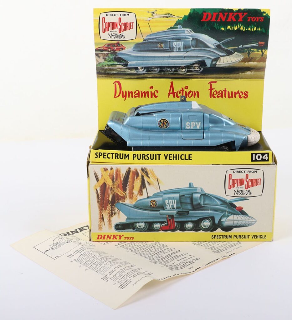Dinky Toys Boxed 104 Spectrum Pursuit vehicle direct from Captain Scarlet And The Mysterons , metallic blue body, white front bumper, front hatch opens to fire rocket, side hatch opens and seat automatically lowers Capt. Scarlet to ground, rear track unit can be raised and lowered, twin aerials fold down. One rocket and instructions, in near mint original condition, inner card illustrated stand is excellent, has some tiny tears and rubbings to base of box where model sits, with outer illustrated box, in near mint original condition