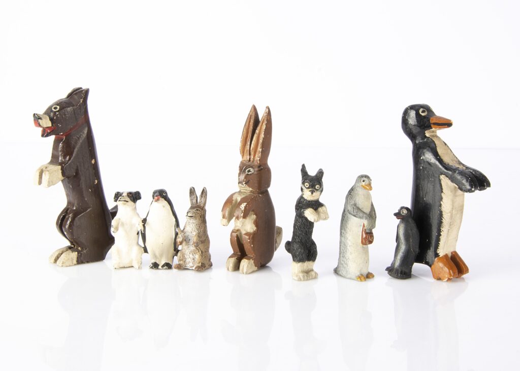 Pip Squeak and Wilfred toy figures, a painted carved wooden set —4in. (10cm.) high; a moulded glass Squeak (missing paste eye); a composition Aunty and Pip; and a hollow-cast German lead terrier, penguin and rabbit