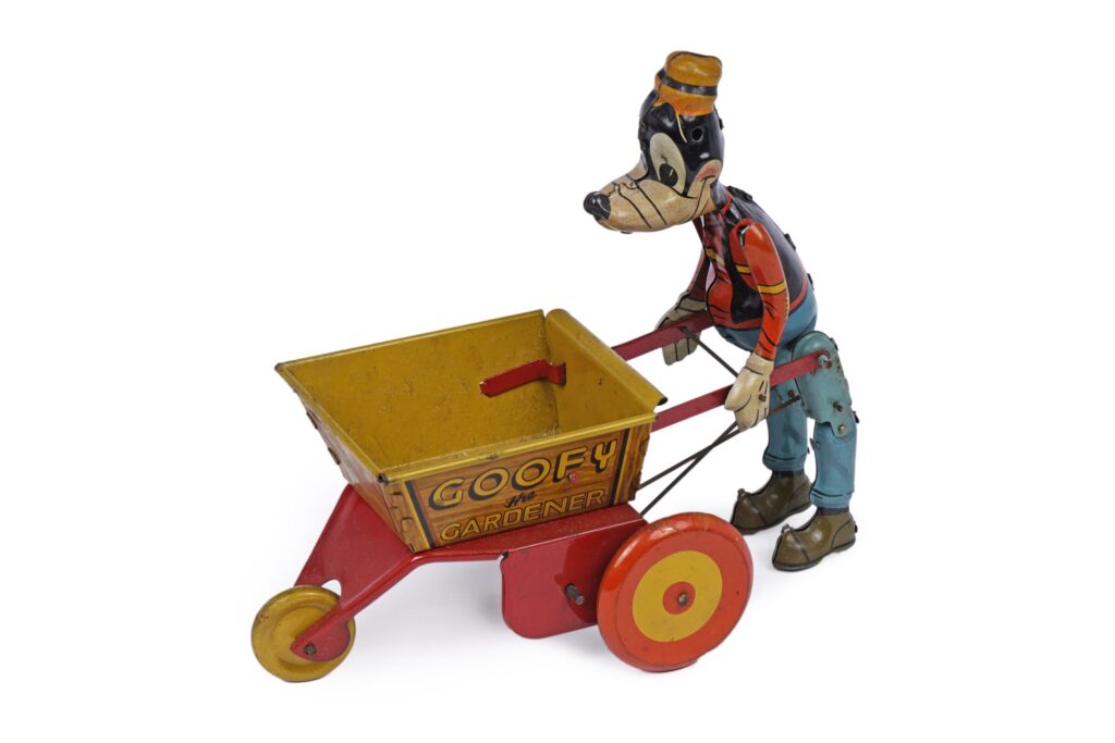 A Marx Toys 'Goofy The Walking Gardener' clockwork tinplate toy, modelled holding a wheelbarrow, 22 x 20cms high, with original box