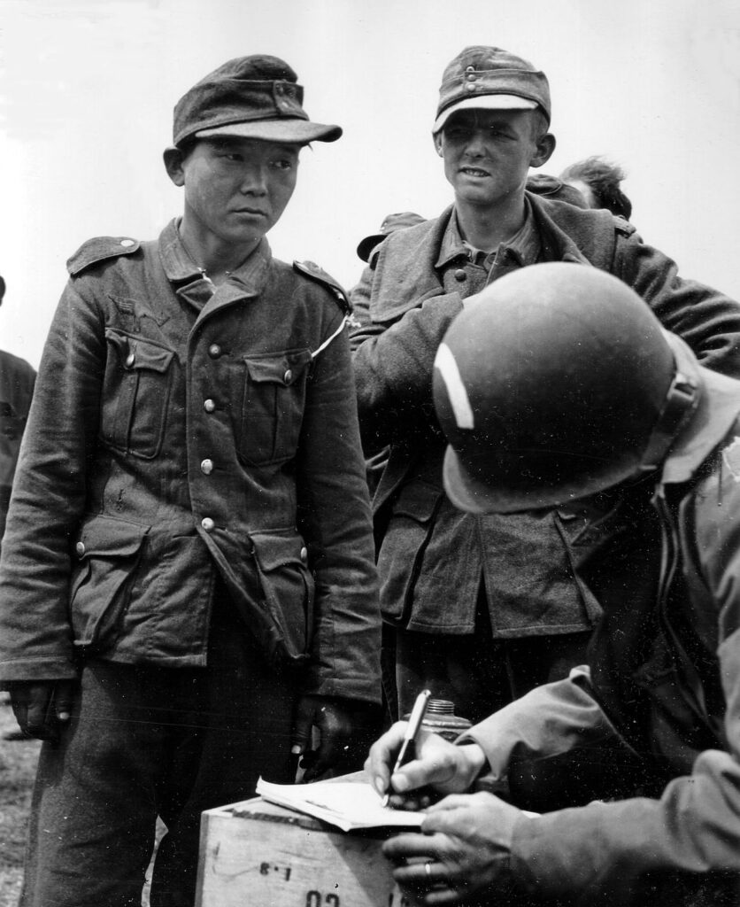 Dismay and loneliness is written on the face of this young Japanese man, often alleged to be Yang Kyoungjong, wearing a Nazi uniform, in a roundup of German prisoners on the beaches of France. The Japanese man is giving his name and number to an American Army captain., 1944. There is no direct evidence that the man in the photo is Yang Kyoungjong. The official caption for the photo only refers to him as "young Jap". Photo: U.S. National Archives and Records Administration