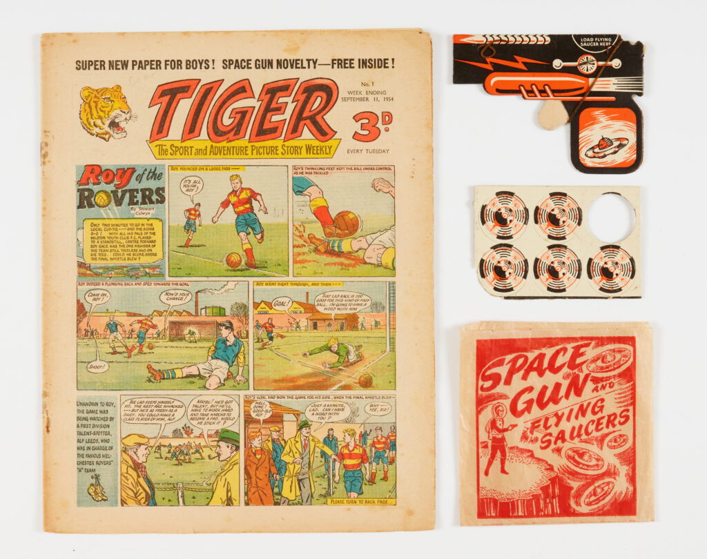 Tiger 1 (1954) wfg Space Gun and 5 (of 6) carded Flying Saucer bullets in original bag. Tiger heralded the first Roy of the Rovers story by Stewart Colwyn (Frank S. Pepper) and Rockfist Rogan by Hal Wilton. Cream/light tan pages with rusty staples [vg], Space Gun, Flying Saucer bullets and illustrated bag flat and fresh