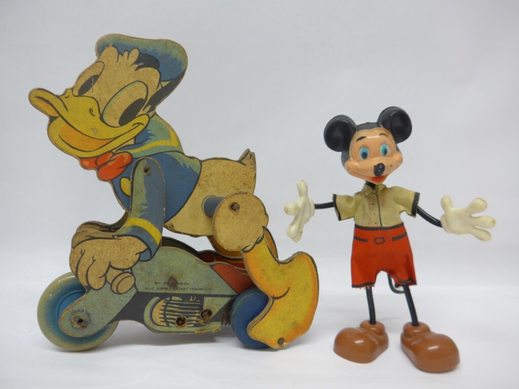 Two vintage Walt Disney character toys to include Chad Valley clockwork wooden Donald Duck on motorcycle, 19cm tall, and Marx bendable Mickey Mouse figure, 14.5cm tall