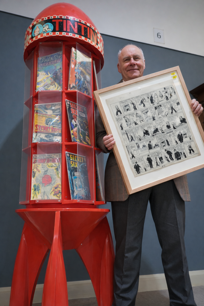 John Bullock-Anderson, Head of Comics at Anderson & Garland, with a piece of "Oor Wullie" art by Dudley D. Watkins featured in the auction, along with a unique "Tintin" inspired bookcase