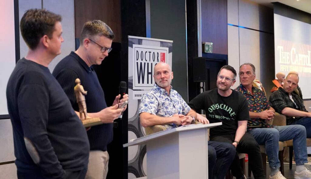 Terrance Dicks sons, Jonathan and Oliver, present writer Peter McTighe (leaning, black t-shirt), with the Doctor Who Society Terrance Dicks Award at Capitol 50. Photo: Andy Richards