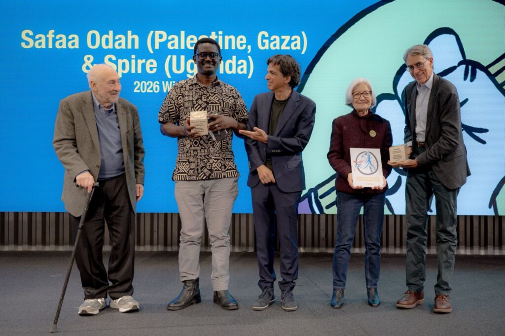 From left to right: Joseph Stiglitz, Nobel Prize laureate in economics; Jimmy “Spire” Ssentongo, 2026 co-laureate of the award; Patrick Chappatte, President of the Foundation; Marie Heuzé, Co-president of the Foundation, holding a self-portrait of Safaa Odah, co-laureate of the award still blocked in Gaza; and Ken Roth, former director of Human Rights Watch and member of the Advisory Board. | Photo: Anastasia Malpertuis, Lensevolve Photography, for the Freedom Cartoonists Foundation