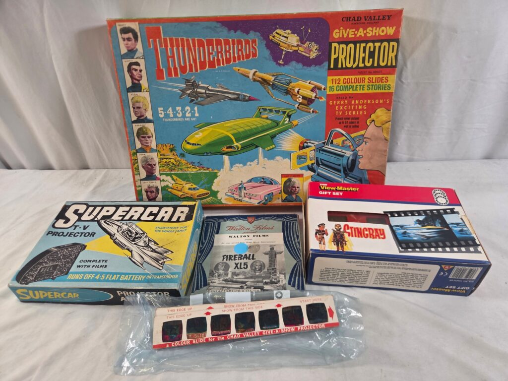 Gerry Anderson projection and film related toys comprising a CHAD VALLEY 'Thunderbirds' projector and unboxed 'Fireball XL5', 'Supercar' and 'Stingray' slides, a BELL TOYS 'Supercar' projector, a 'Stingray' VIEWMASTER set and a Walton Films 8mm 'Fireball XL5 film 'Planet 46' - VG in G/VG boxes (where boxed) (5)