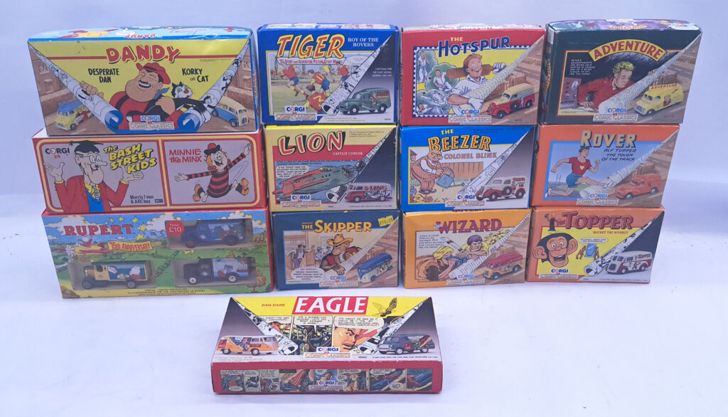 Corgi, a group of thirteen boxed Comic Classics diecast model sets including ref. 98754, 98755, 98756, 98965 and others.

The lot comprises:

• Corgi The Dandy – a two-vehicle set comprising a Bedford CA van and a Morris J van in Desperate Dan and Korky the Cat liveries.

• Corgi Tiger – a Morris 1000 van in green Roy of the Rovers livery.

• Corgi The Hotspur – a Ford Popular van in red and cream The Hotspur livery.

• Corgi Adventure – a Bedford CA van in yellow Adventure livery.

• Corgi The Bash Street Kids & Minnie the Minx – a two-vehicle set comprising a Morris J van and an AEC bus in red and yellow comic liveries.

• Corgi Lion – a Volkswagen van in cream and red Captain Condor livery.

• Corgi The Beezer – a Ford Popular van in cream and maroon Colonel Blink livery.

• Corgi The Rover – a Morris 1000 van in red Alf Tupper The Tough of the Track livery.

• Rupert 75th Anniversary set – a commemorative three-vehicle limited edition set featuring commercial vans in Rupert Bear liveries.

• Corgi The Skipper – a Volkswagen van in blue and cream The Skipper livery.

• Corgi The Wizard – a Morris J van in red and yellow The Wolf of Kabul livery.

• Corgi The Topper – a Morris J van in cream and red Mickey the Monkey livery.

• Corgi Eagle – a two-vehicle set comprising a Volkswagen van and a Bedford CA van in Dan Dare liveries.
Condition appears Good to Excellent. Box is Fair to Good.