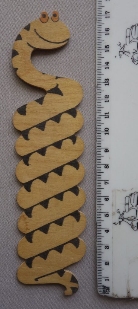 Phil-Comics has been consigned this interesting and unusual balsa wood style item, which appears to be Sid's Snake, from Whizzer and Chips, but it wasn't given away as a free gift with the comic, although there is a possibility it was gifted as a competition prize. For example, in the issue of Whizzer and Chips, cover dated 19th October 1974, there was a competition that gave away £1 per week for a year as a first prize, with 250 other prizes of Bumper Joke Boxes and 500 Whizzer and Chips baseball caps. There's a picture of the joke box, but we don't know if it was literally the box, or a box with various joke type items (we suspect the latter), so there's a chance it came as one of the items in here, but Phil Shrimptin admits he is merely speculating here. The jury is out as to where this originated. The auction house has certainly not seen another one on the market. An alternative solution is that it's just a one-off home made item, albeit one of very good quality, with beautifully smooth, rounded edges down the length of the tail. Nice ink print, too. It measures just under 7 inches in length and 1.5 inches in width.